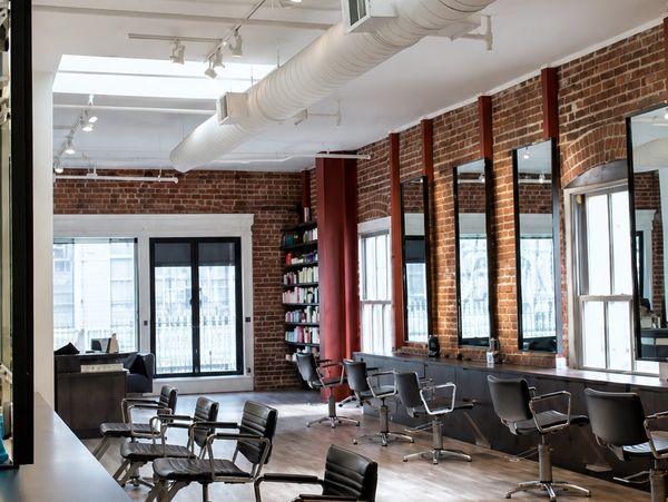 Modern hair salon with exposed brick walls and multiple styling stations.