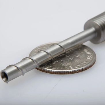 A small metal stepped tool rests on a U.S. quarter for scale.