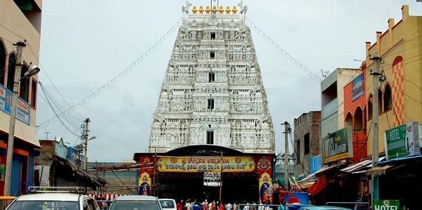 The towering white temple gopuram amidst a busy street scene.