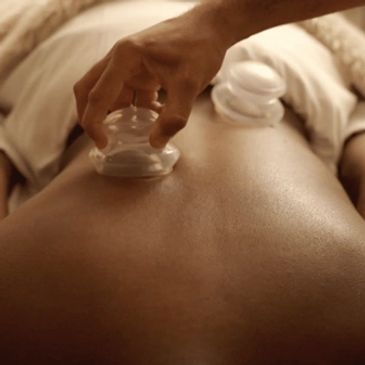 Hand performing cupping therapy on a person's back.