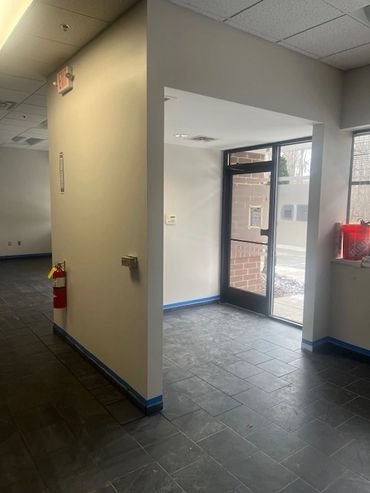 Empty indoor hallway with tiled floor and glass door.