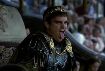 Man in ancient Roman attire sticking out his tongue.