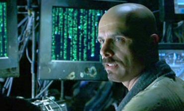 Man looking at screens with green code.