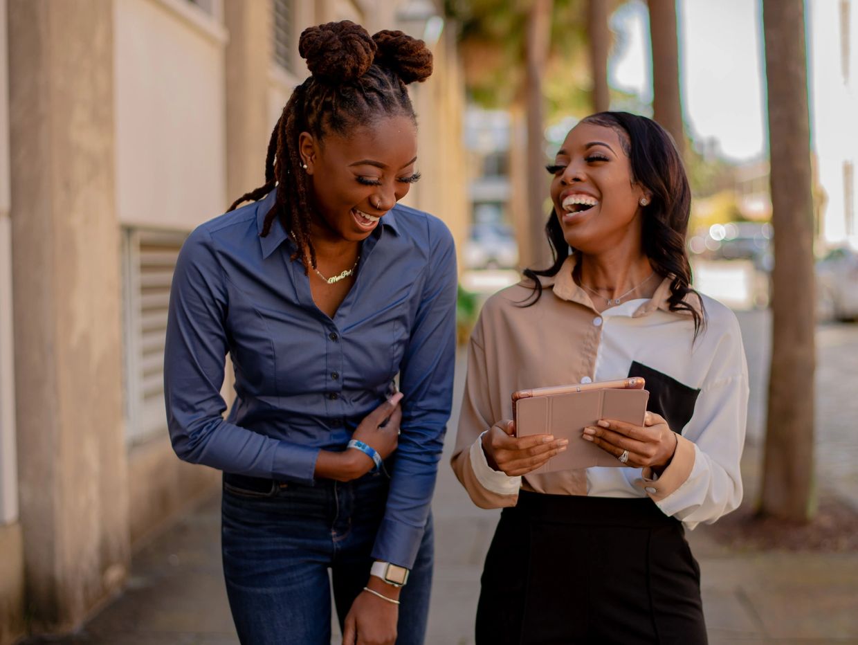 Two women laughing together outdoors.