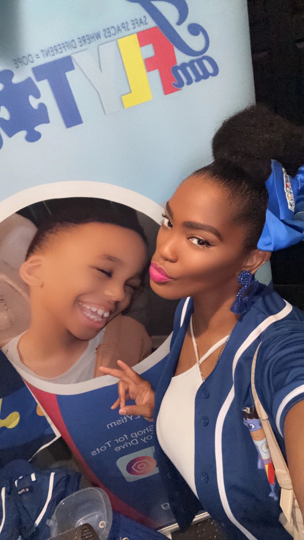 Woman posing for a selfie with a smiling child poster in the background.
