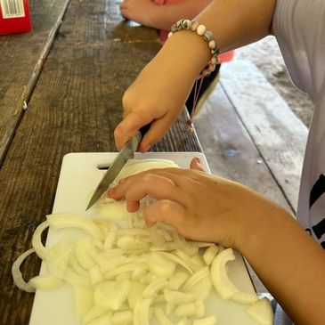 Young girl using a knife to cut onions 