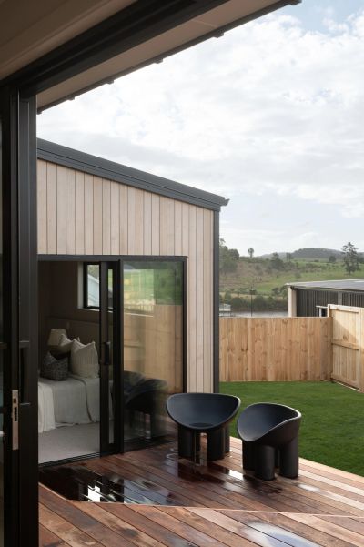 Modern backyard with black chairs and wooden deck.