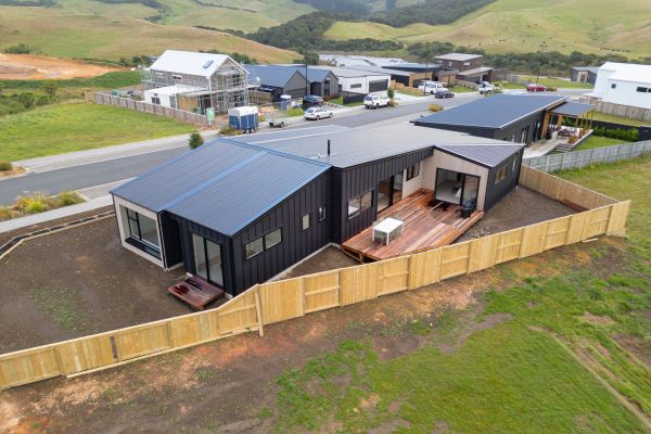Modern black house with a wooden fence and deck.