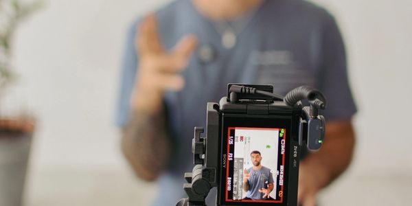 A person recording a video with a camera, showing a hand gesture.