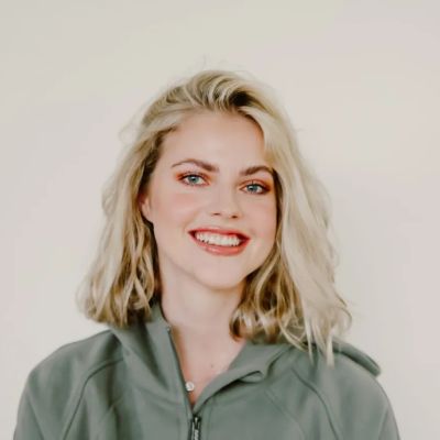 Smiling young woman with blonde hair in a green jacket.
