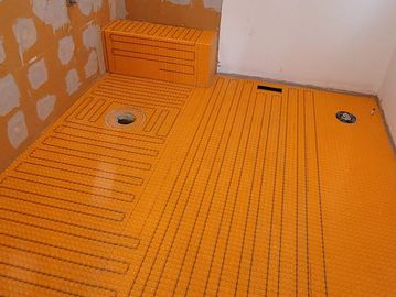 Orange waterproofing and heating mat installed in a shower under construction.