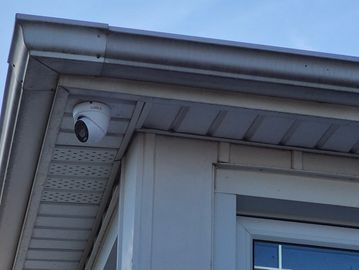 Security camera installed under the eaves of a house.