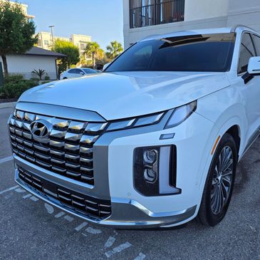 A white Hyundai SUV parked in a residential area under daylight.