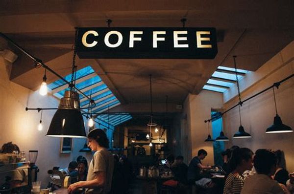 Cozy coffee shop with warm lighting and patrons enjoying their drinks.