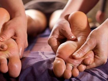 Hands giving a foot massage on bare feet.