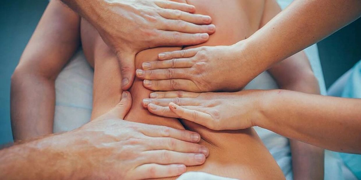 Multiple hands massaging a person's back simultaneously.