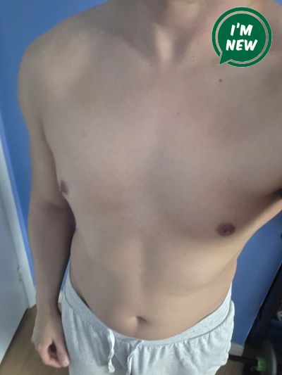 Shirtless person wearing light shorts in a room.