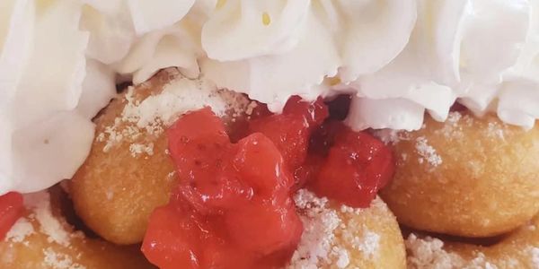 Fried dough balls with strawberry sauce and whipped cream.