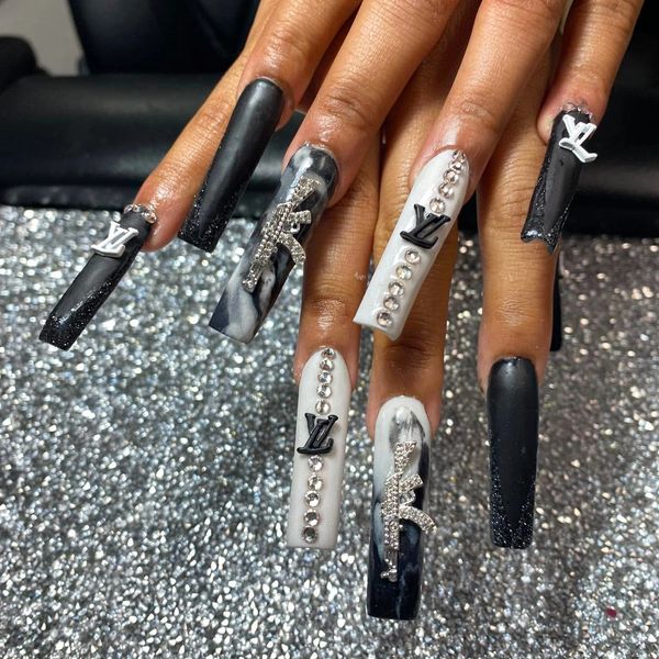 Black and white long nails with rhinestones and Louis Vuitton charms.