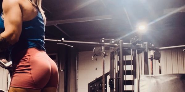 Woman with muscular legs and arms working out in a gym.