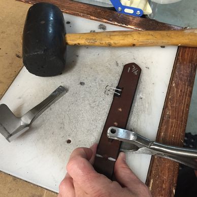 Mike Dow punching holes in a custom belt.
