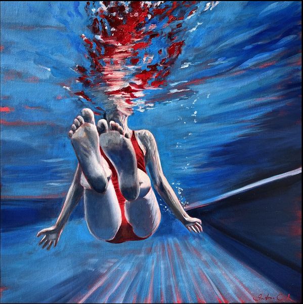 Underwater scene in a pool of a woman in red costume. Feet lifted up with hands at her side.