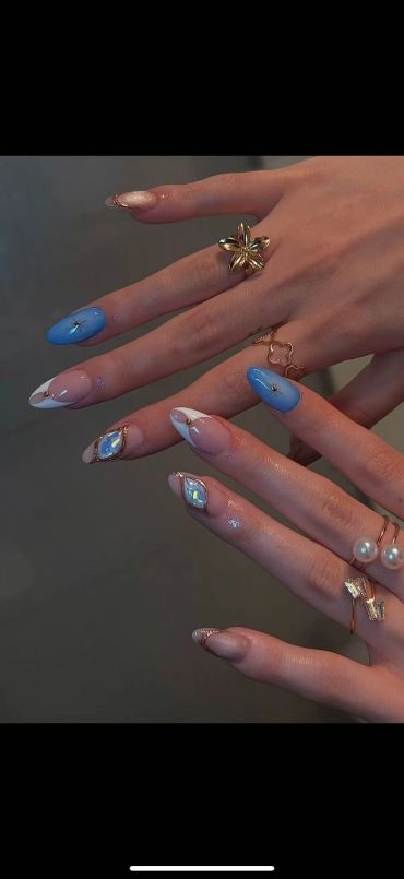 Elegant blue and nude nails with gold accents and crystal details.