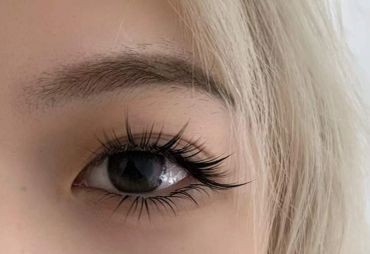 Close-up of an eye with long, curled eyelashes and blonde hair.