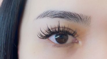Close-up of an eye with long, curled eyelashes and well-groomed eyebrow.
