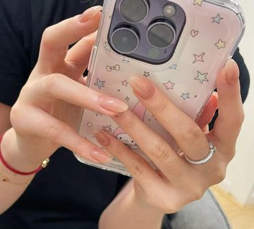 Hands with glossy nude ombré nails holding a phone with a starry case.