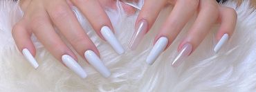 Long nails with glossy white and pearl pink polish on a soft white fur background.