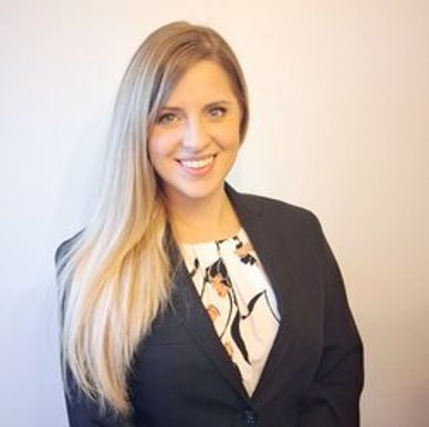 Professional woman with blonde hair smiling, dressed in business attire.