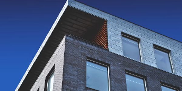 Modern building corner with large windows against blue sky.
