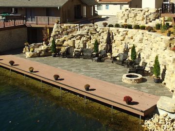 Outdoor seating area by a stone wall and dock.