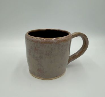 A simple ceramic mug with a handle, light brown with a glossy finish.