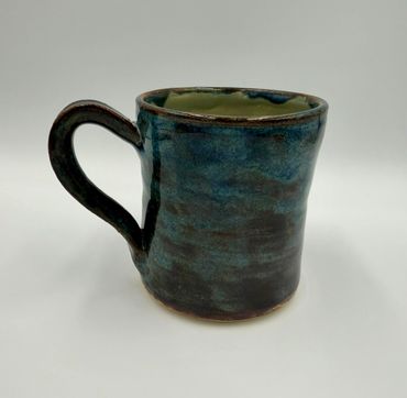 Handcrafted ceramic mug with a blue-green glaze and a sturdy handle.