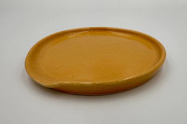 A simple, round mustard-yellow ceramic plate with a small lip.