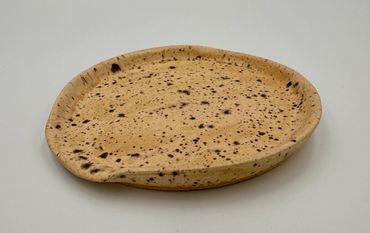 A flat, round, toasted bread with speckled burn marks.