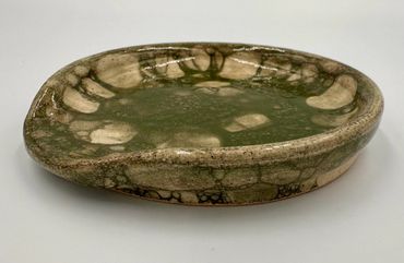 Handcrafted ceramic plate with earthy green and beige glaze patterns.