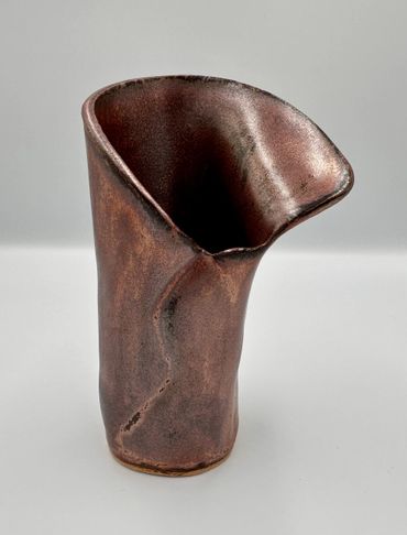 A uniquely shaped ceramic vase with a rustic brown finish.