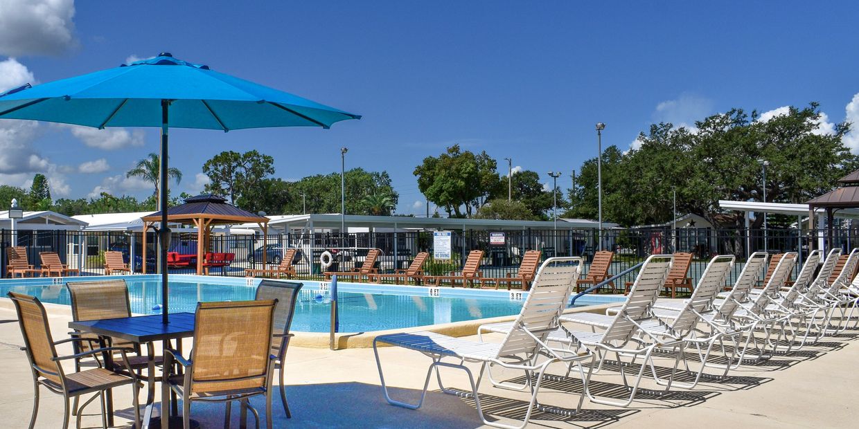 Resort heated swimming pool surrounded by deck chairs and umbrellas at Rice Creek RV Resort ground.