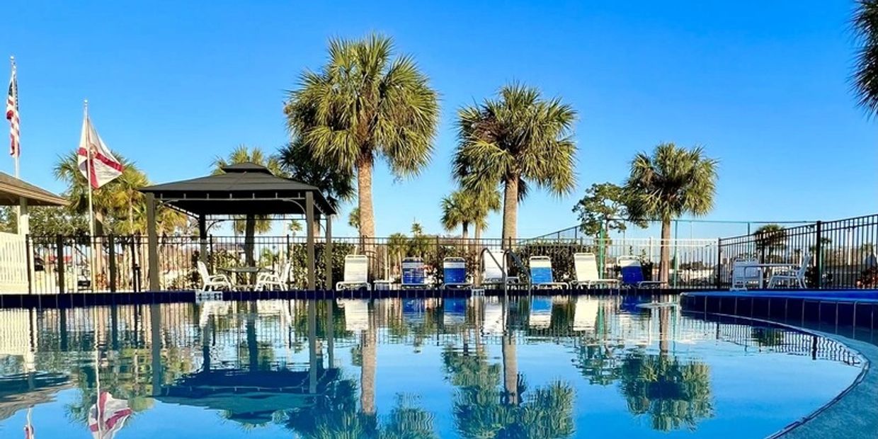 Palm trees reflecting on the water of the pool at Sundance Lakes RV Resort