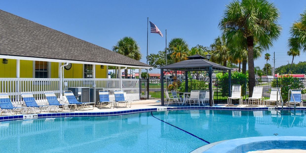 Sparkling blue swimming pool and poolside lounge chairs at Sundance Lakes RV Resort.