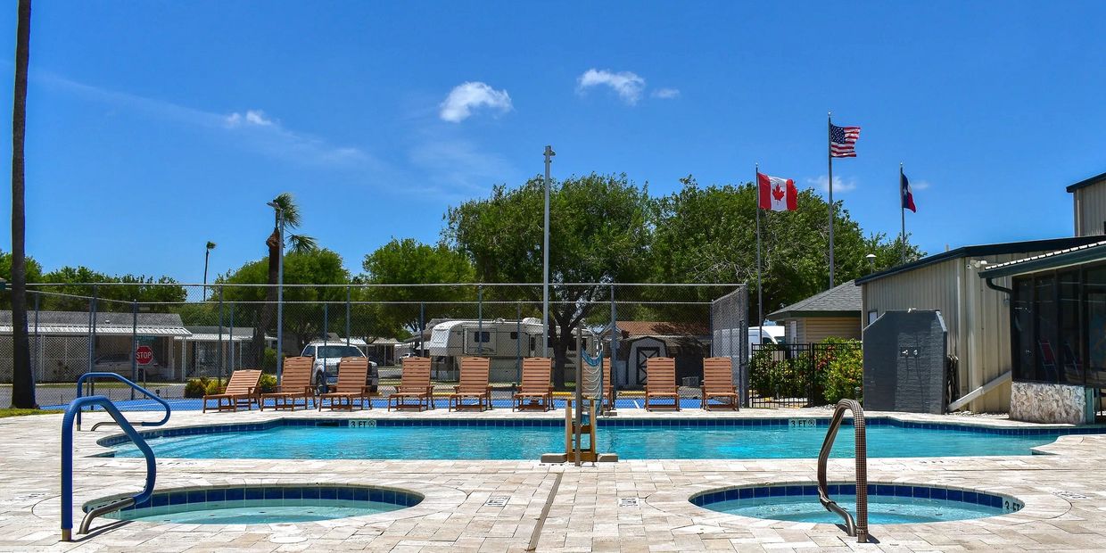 Tropical outdoor pool with palm trees and comfortable lounge chairs in sunshine