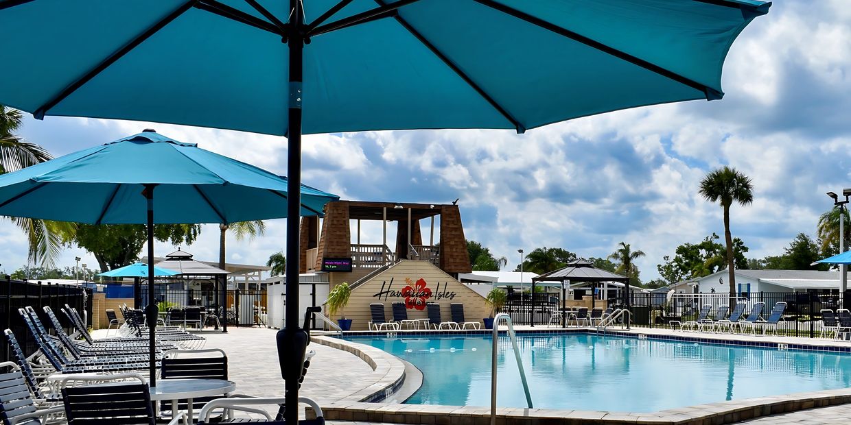 Olympic sized heated swimming pool with palm trees and blue sky background at Hawaiian Isles RV Reso