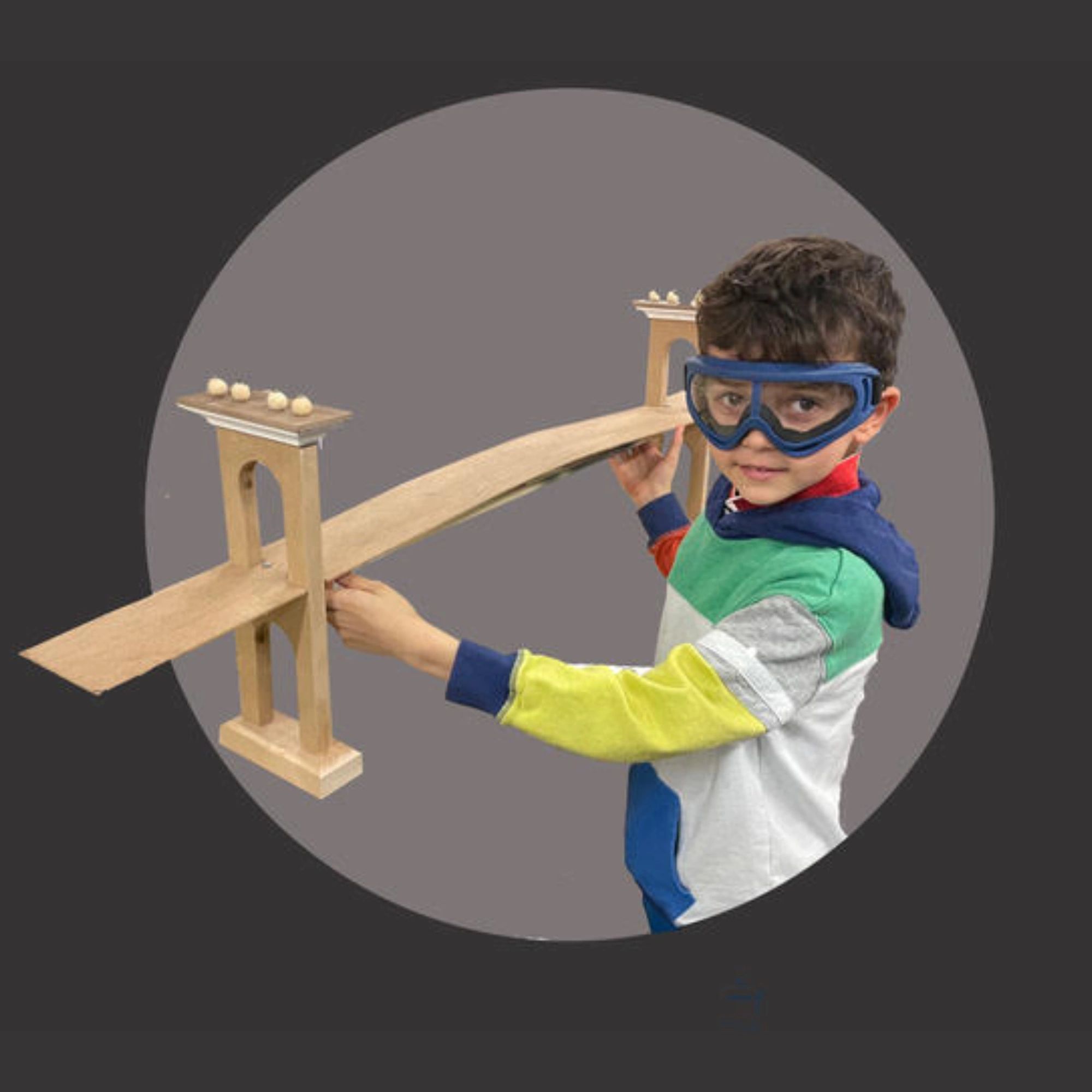 A kid holding a wooden bridge that he built in Dumbo Workshop