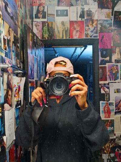 Person taking mirror selfie with camera in colorful room.