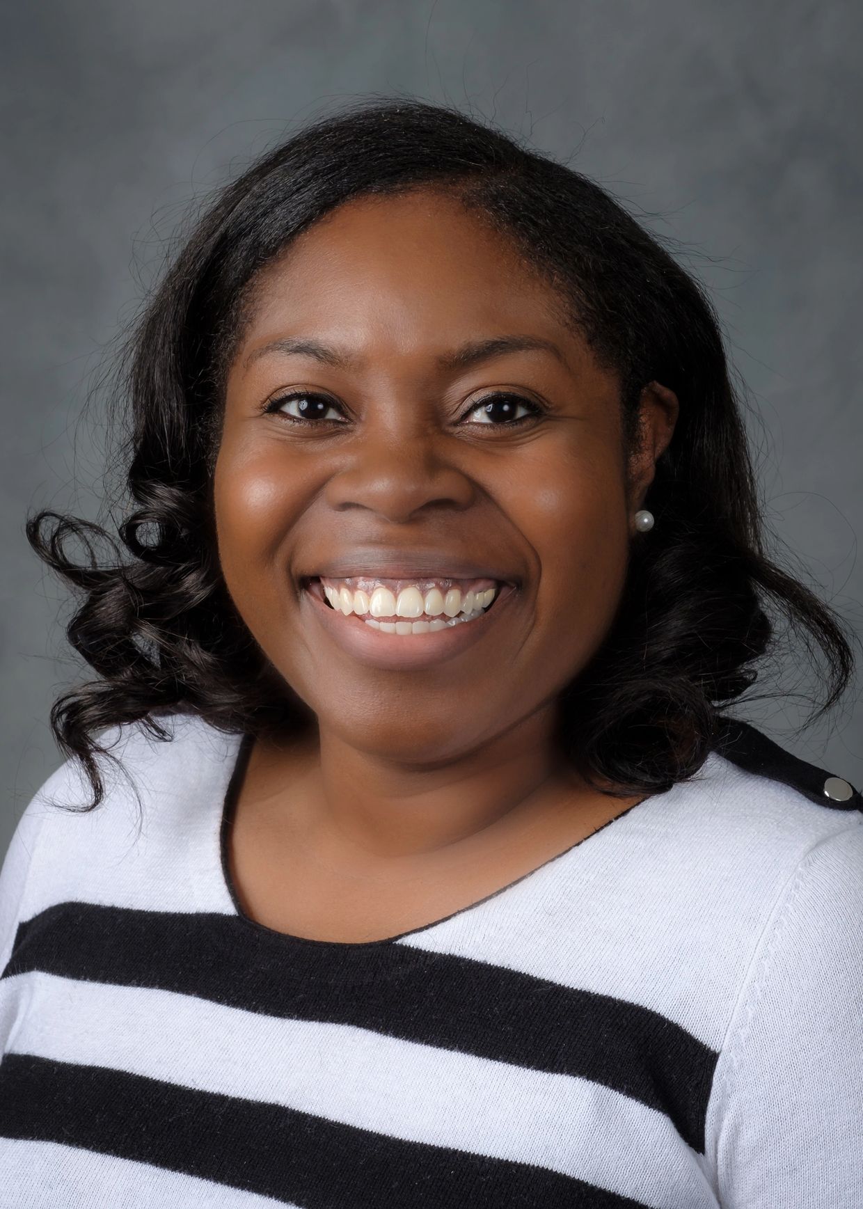 Smiling woman with curly hair wearing a black and white striped sweater.