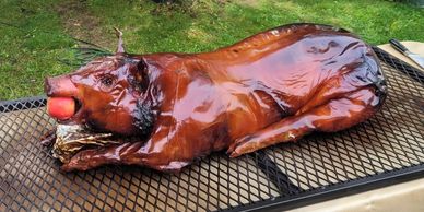 A whole roasted pig with an apple in its mouth on a grill.