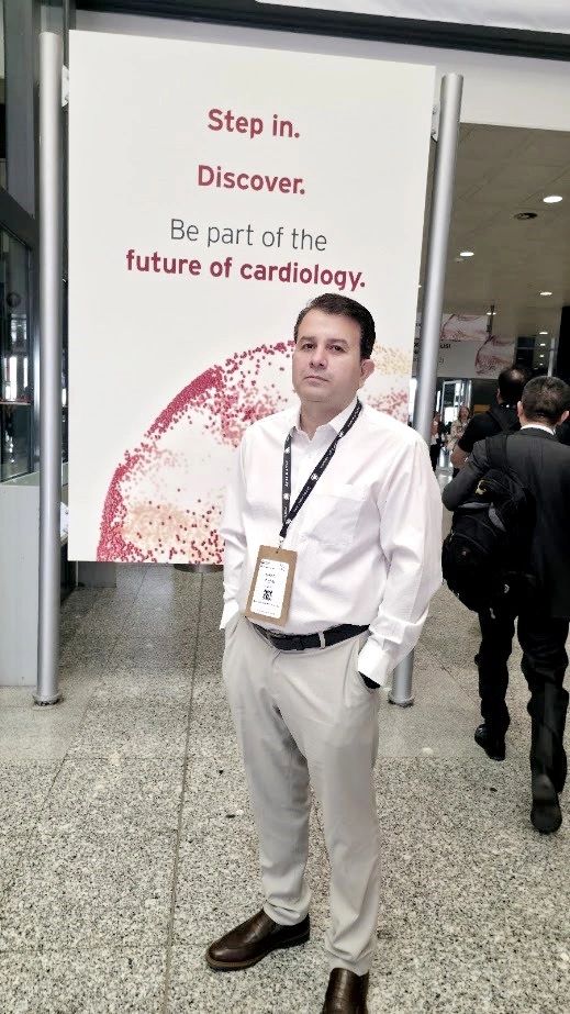 Man in white shirt at a cardiology event with a sign about future cardiology.